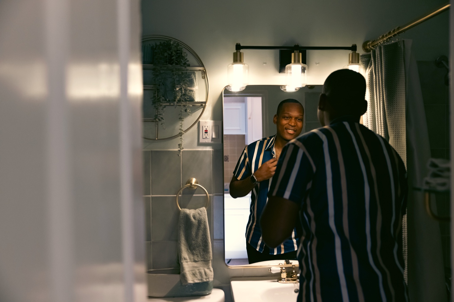 Man at the bathroom mirror during his evening routine in warm light